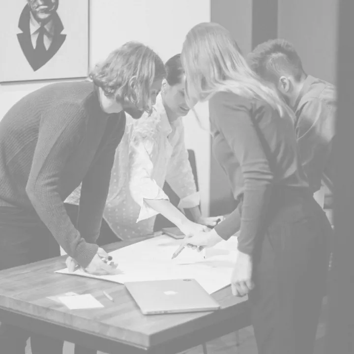 A group of people standing around a wooden table.