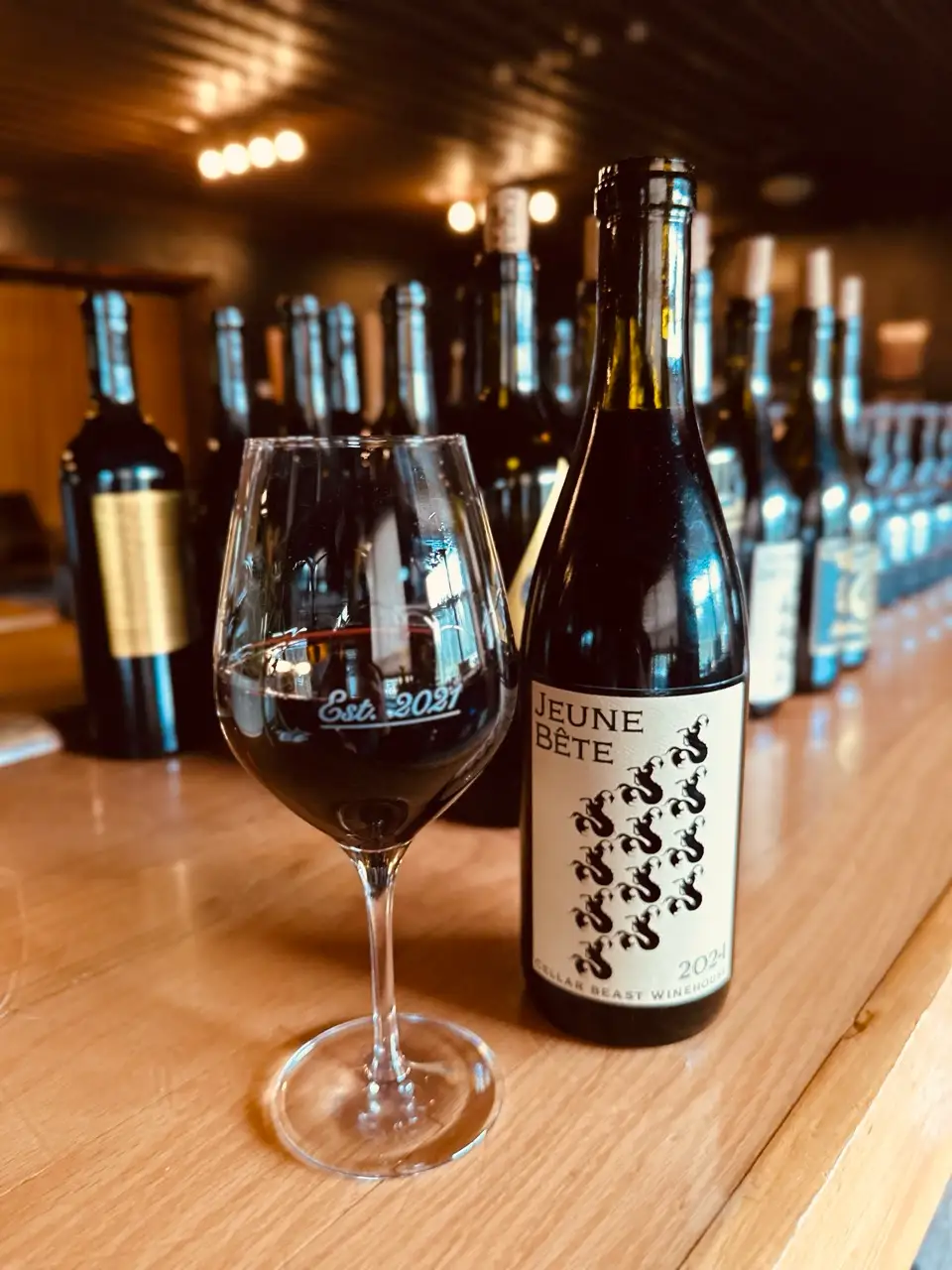 Cellar Beast Syrah vs Malbec focus with a glass and bottle of Jeune Bete red wine on the table