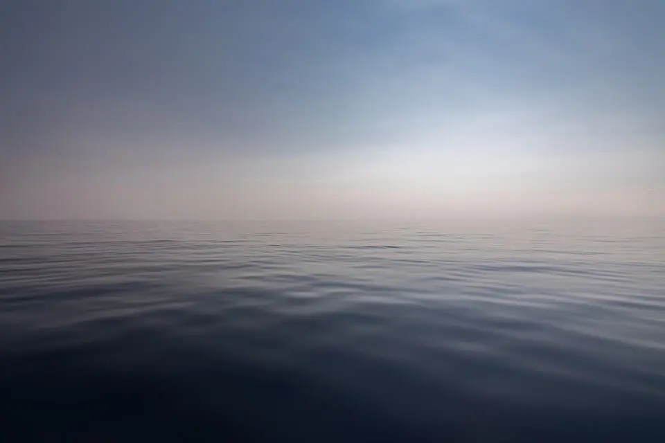 Still body of water against a calm sky