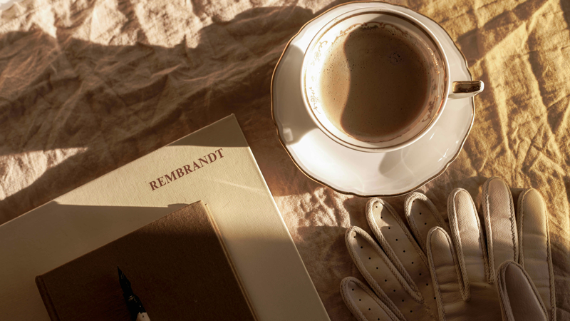 An open notebook beside a coffee cup in warm morning light
