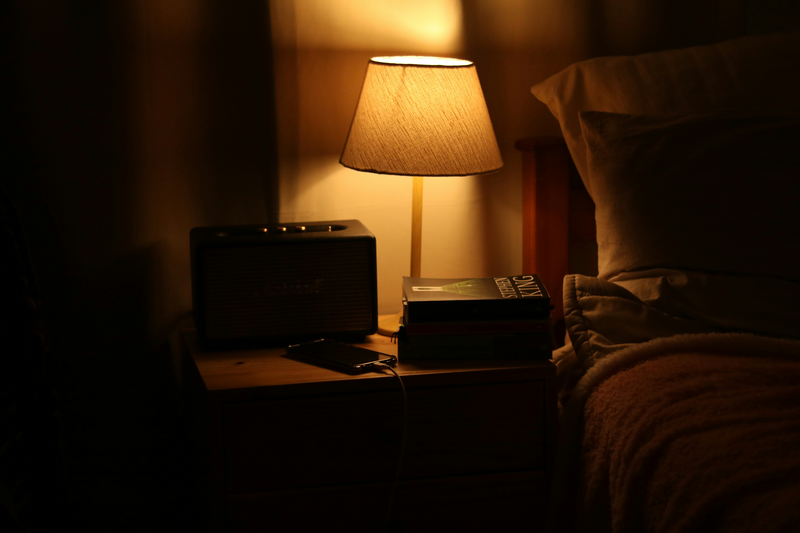 A warm bedside lamp glowing on a small nightstand at night.