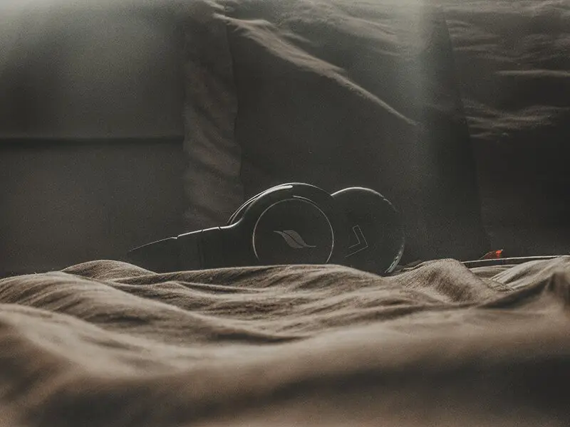 Headphones laying on bed for music as a relaxing activity before bed