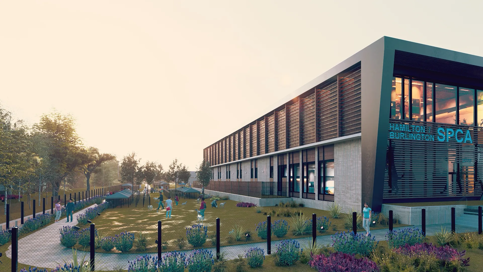 Modern SPCA building with a fenced outdoor area where people are walking and interacting with dogs under a pale sky.