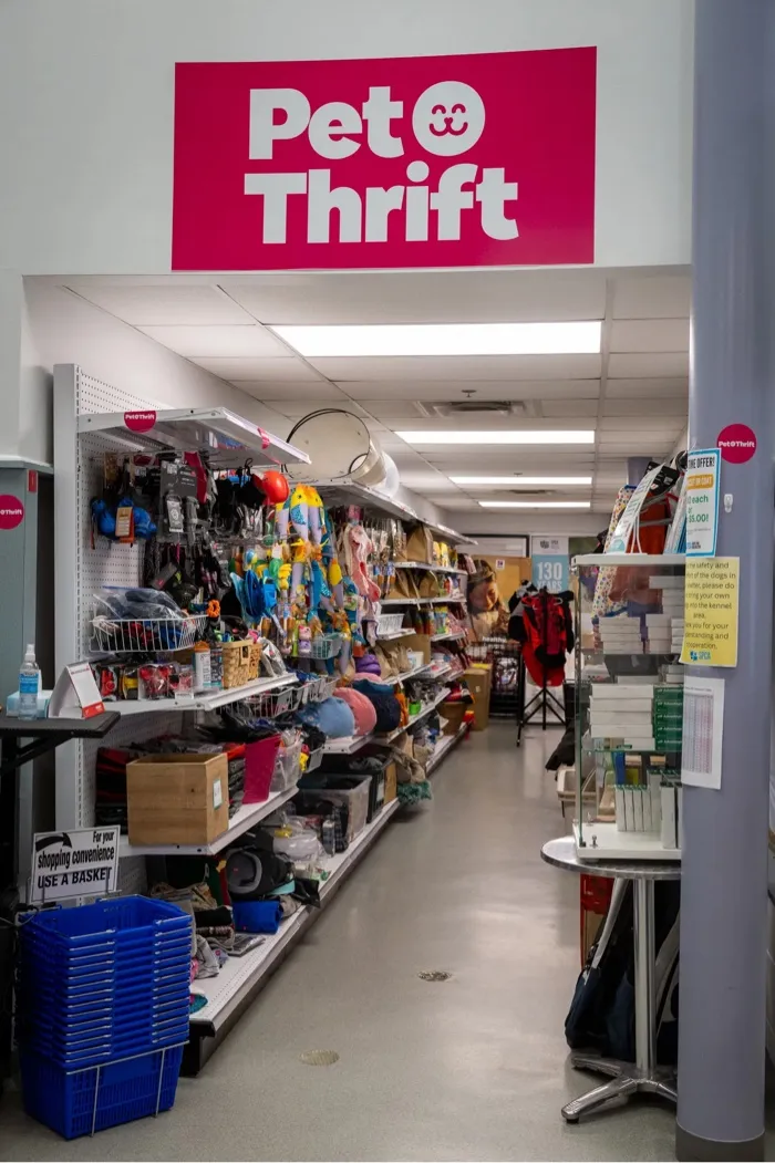 Interior aisle of a Pet Thrift store with shelves stocked with pet supplies and toys.