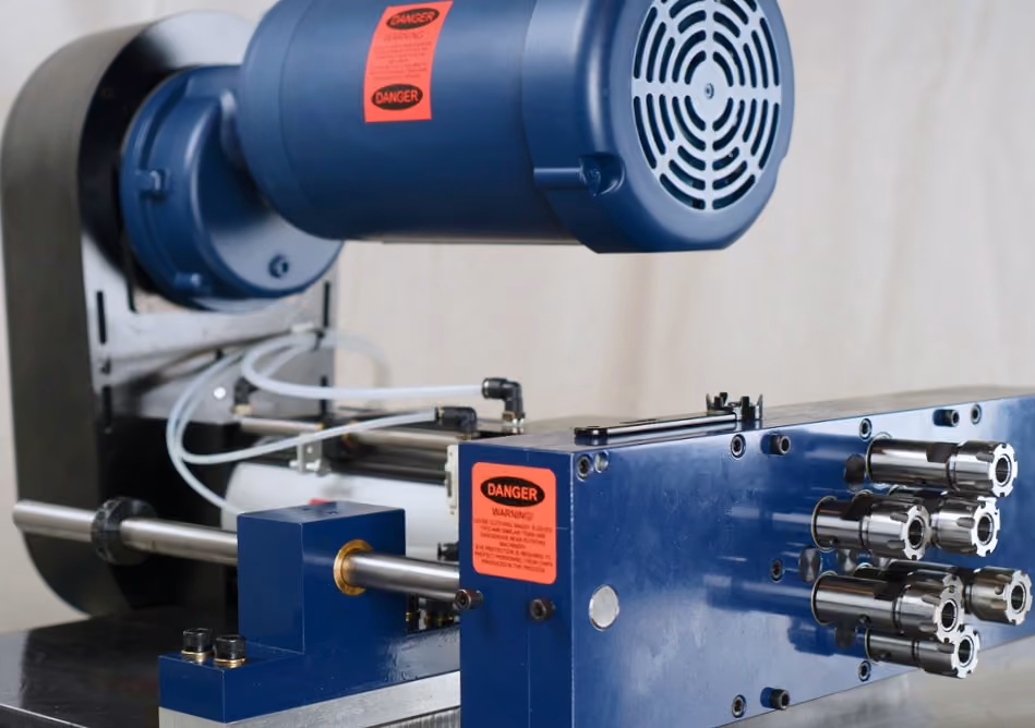 Close-up of blue industrial machine with metal drill components and warning labels.