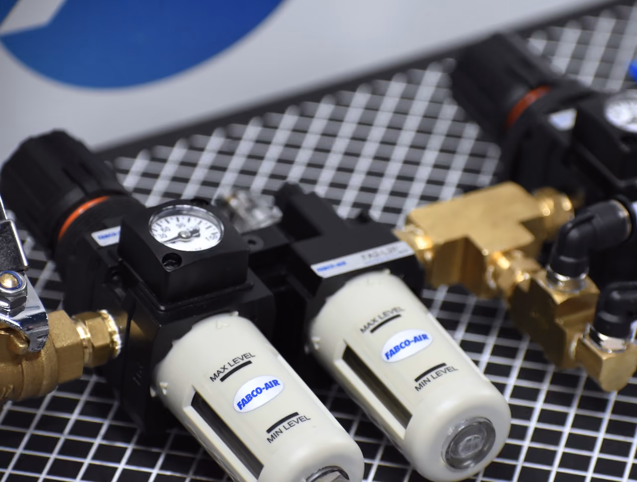 Close-up of two Fabco-Air pneumatic filter regulator lubricator units with gauges and brass fittings.
