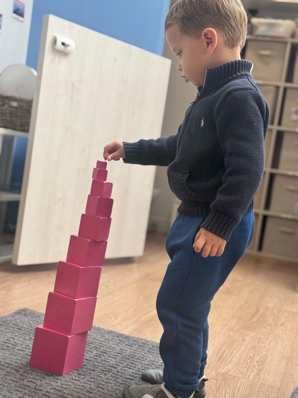 Individualized support at school: child concentrates while doing the Pink Tower activity