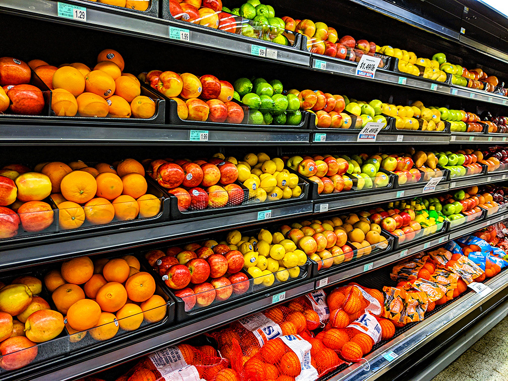 Brightly illuminated grocery store produce aisle with LightLogics' intelligent LED lighting, making the fruits appear vivid and appetising.