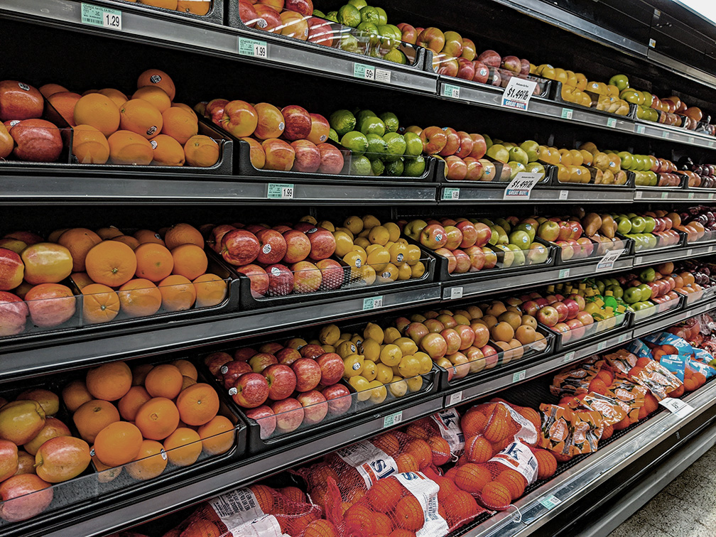 Dimly lit grocery store produce aisle. The fruits appear lacklustre and bleary.