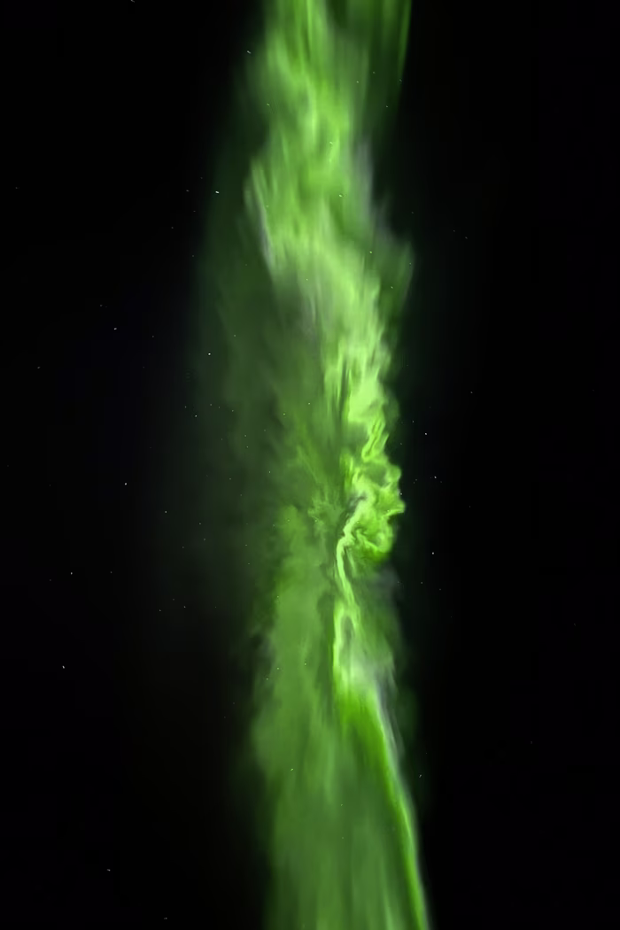 Vertical strip of bright green northern lights glowing against a dark night sky with stars.