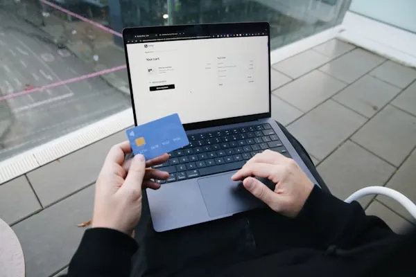 Sujetando una tarjeta de crédito mientras finaliza una compra en línea, mostrando la perfecta integración de SumUp para pagos seguros.