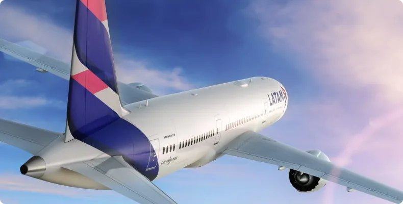 White LATAM airplane flying in the sky with a purple, pink, and red patterned tail fin under a partly cloudy blue sky.