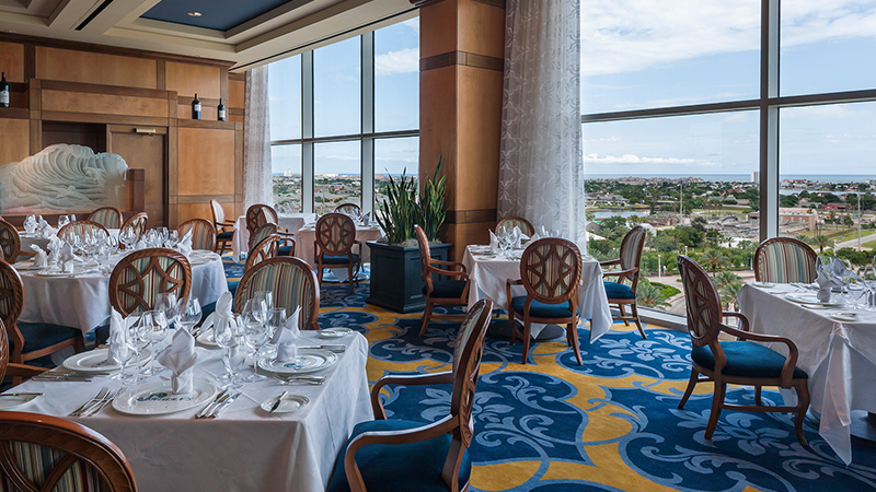 Shearn's dining room with white tablecloths and floor-to-ceiling windows overlooking Galveston