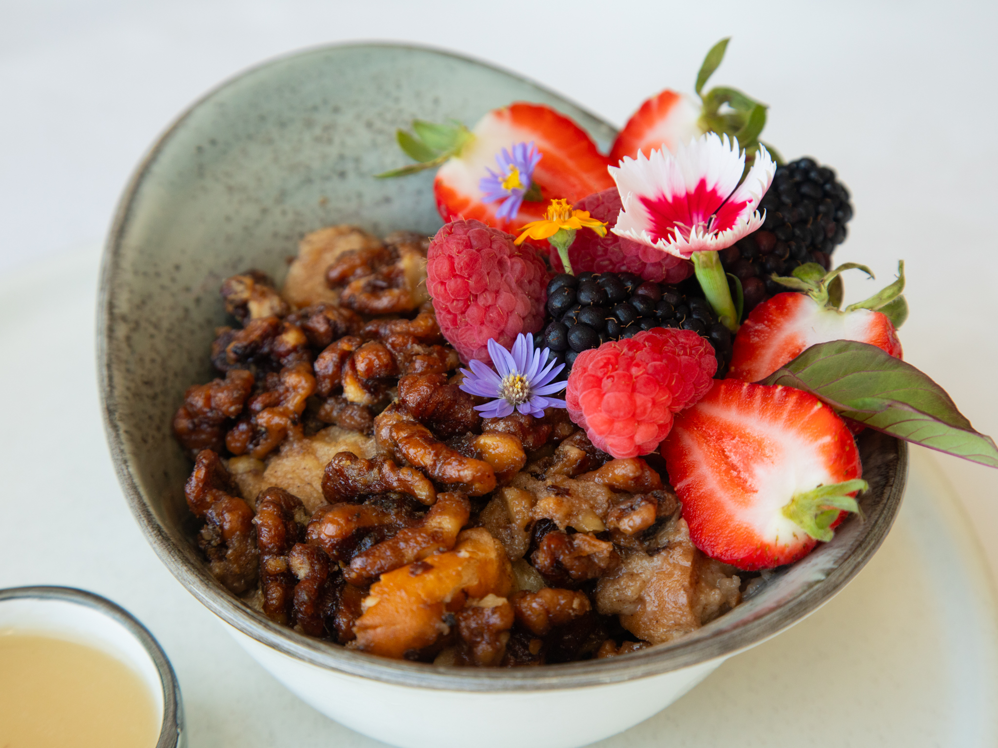 Dessert bowl topped with candied pecans, fresh berries, and edible flowers at Shearn's