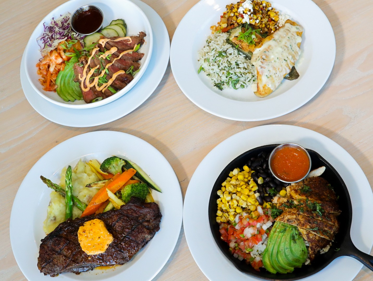 Four entrees including steak, a skillet, and a poke bowl at Café in the Park