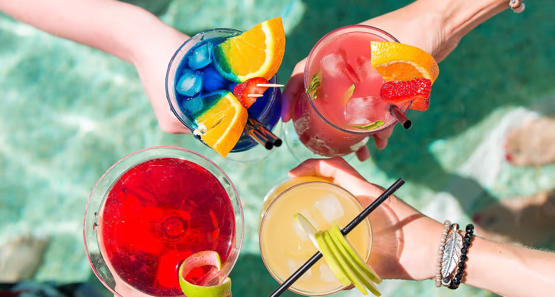 Four glasses seen from above, each filled with a brightly colored tropical drink