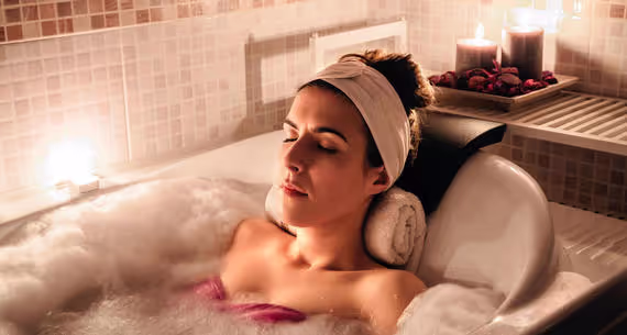 Guest relaxing with eyes closed in a candlelit bubble bath at The Spa at Moody Gardens