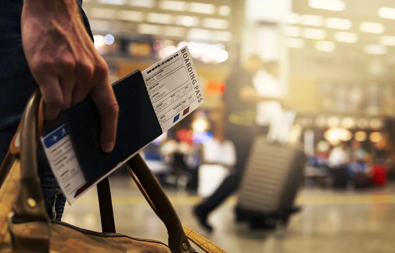a person holding a luggage bag and a ticket