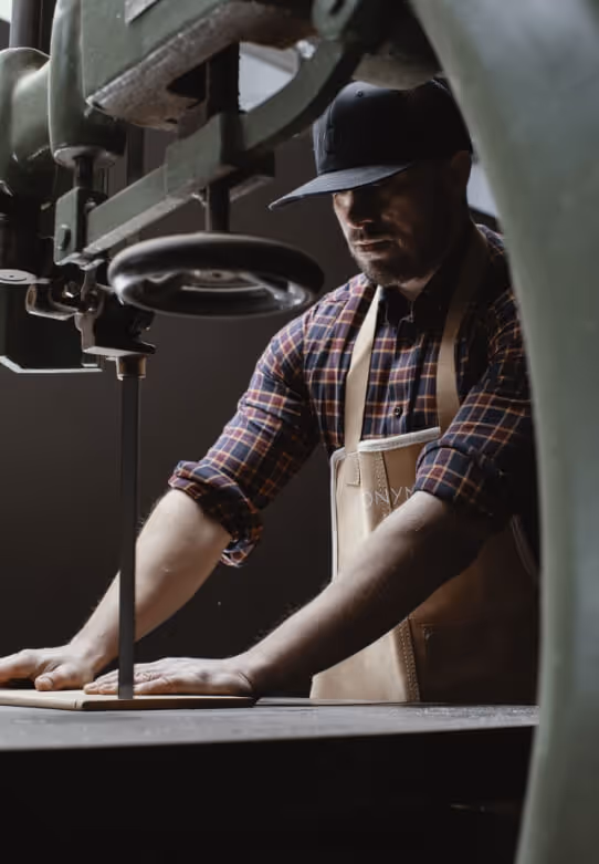 Craftsman using bandsaw to shape wood in Anonymia workshop