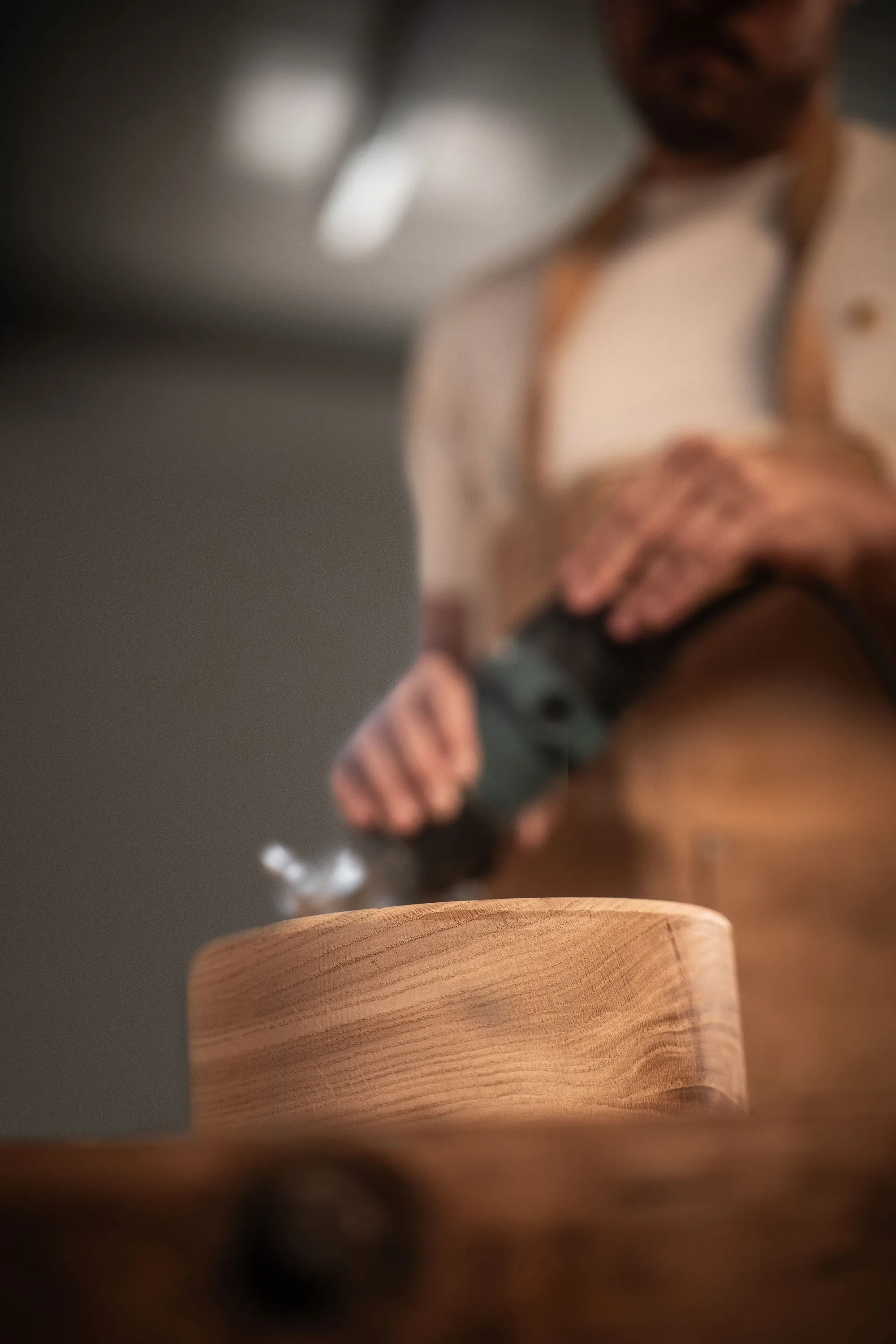 Sanding a round oak piece, the workbench in the foreground