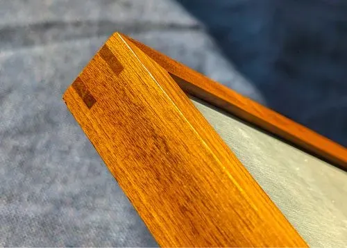 An image of the corner of the Metroboard's walnut wooden frame.