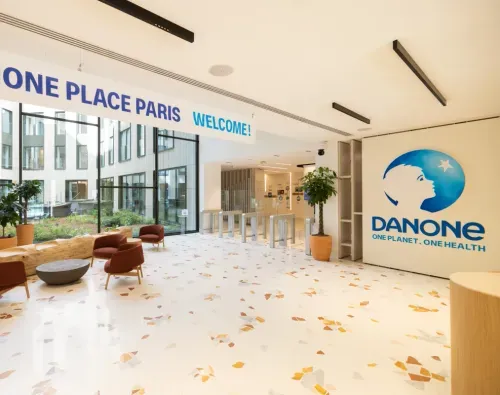 Bright Danone office lobby with terrazzo floor, seating area, plants, and large company logo on wall.