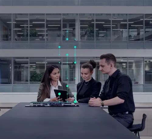 Three professionals discussing a train model on a table with digital data overlay in a modern office.