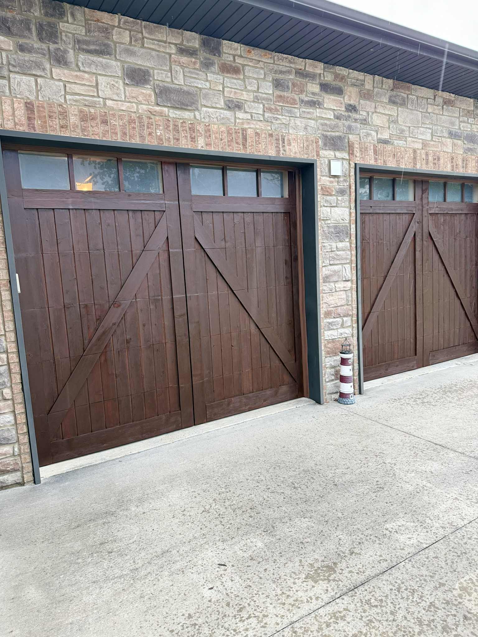 Freshly stained wood garage doors on a stone and brick Colorado home