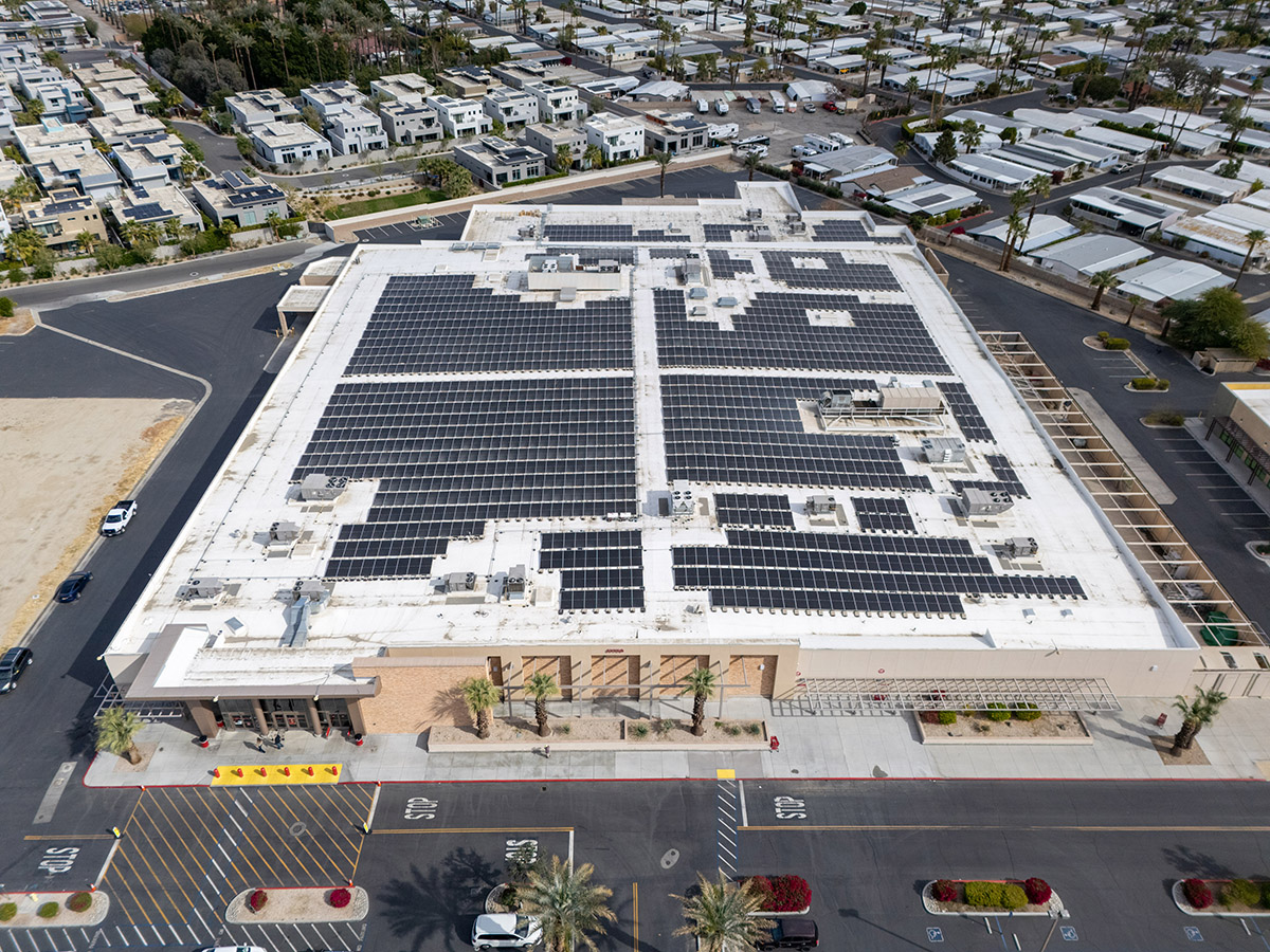 Aerial view of a retail store with an extensive photovoltaic panel system installed on the roof, maximizing energy efficiency.
