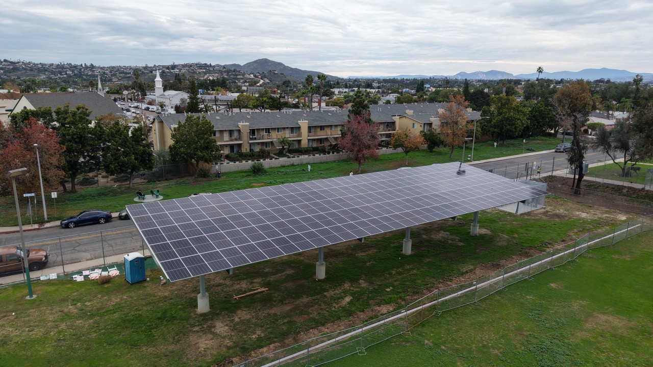 Drone aerial perspective of Pendleton Elementary School DSA solar project with commercial solar carports across campus parking areas.
