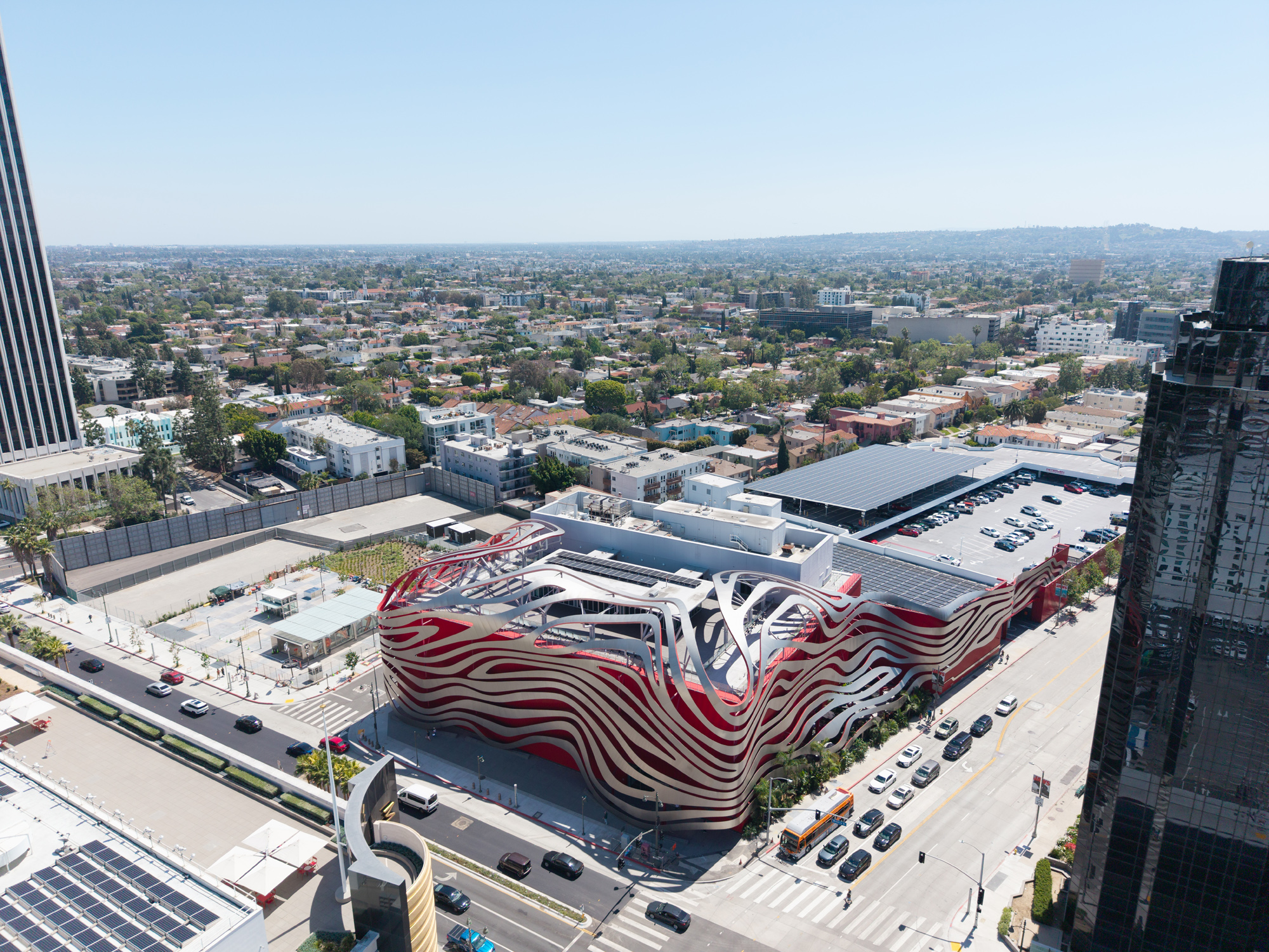 Front-facing aerial of Petersen Automotive Museum with Solar System and Commercial Solar canopy visible behind the building.