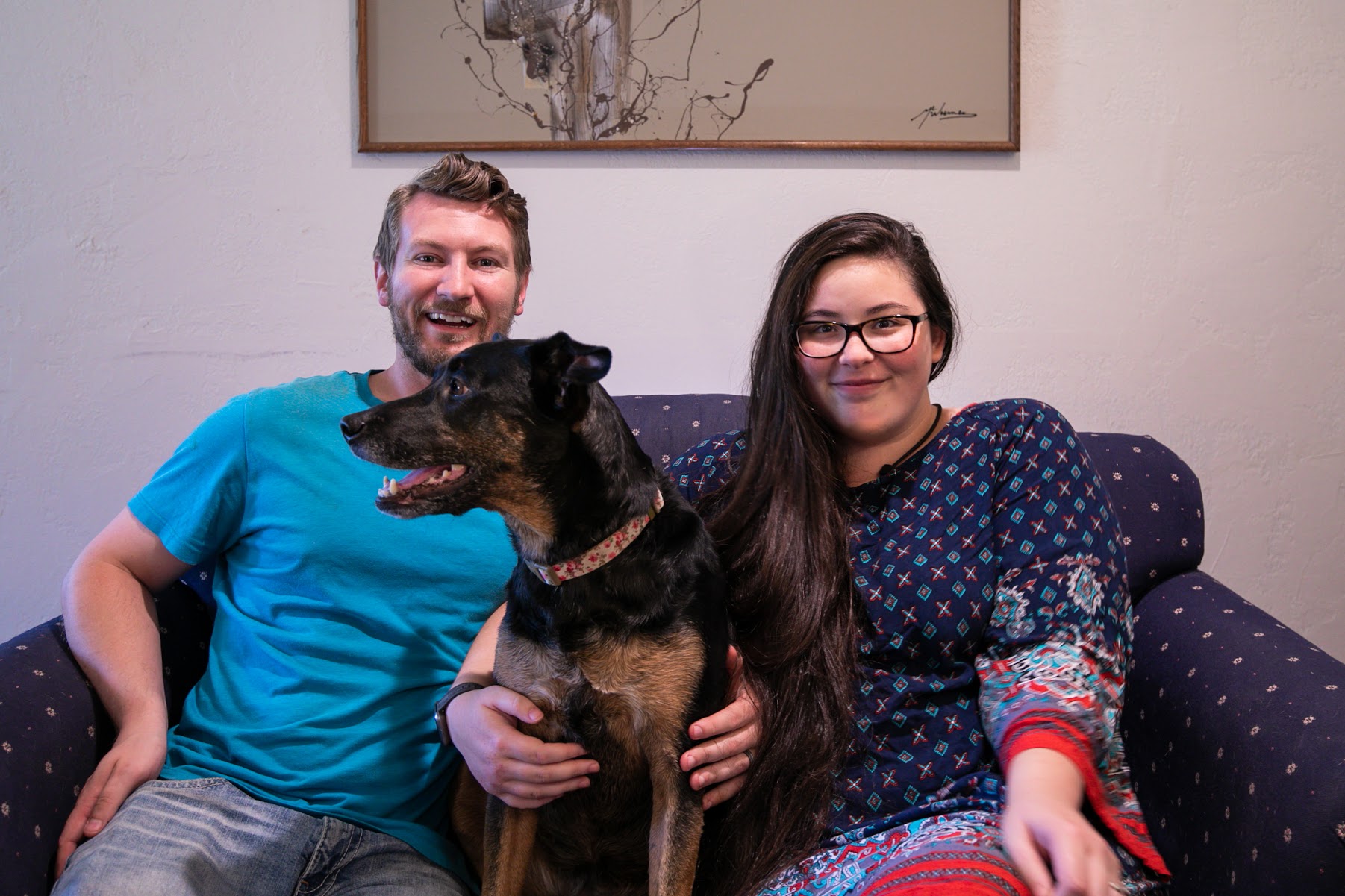 Garrett and Grace Hammonds are sitting on a couch with their dog Carly.