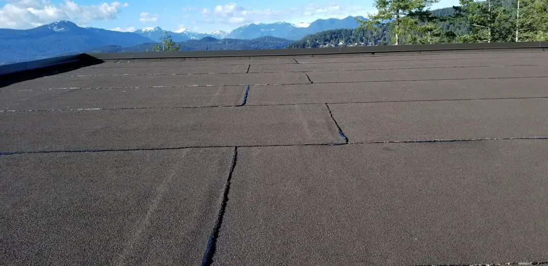 Close view of a finished granulated torch-on cap sheet with tight laps, mountains in the background