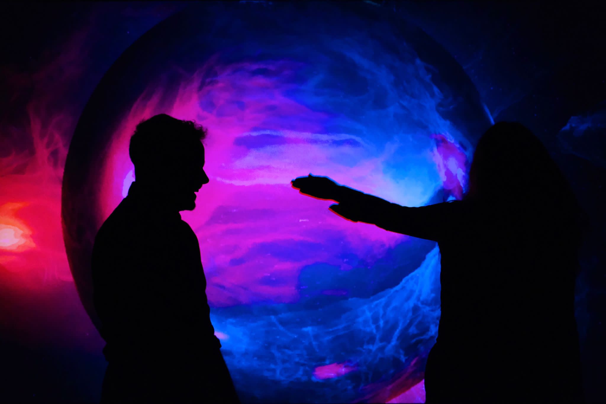 Two people in front of space projected graphics.