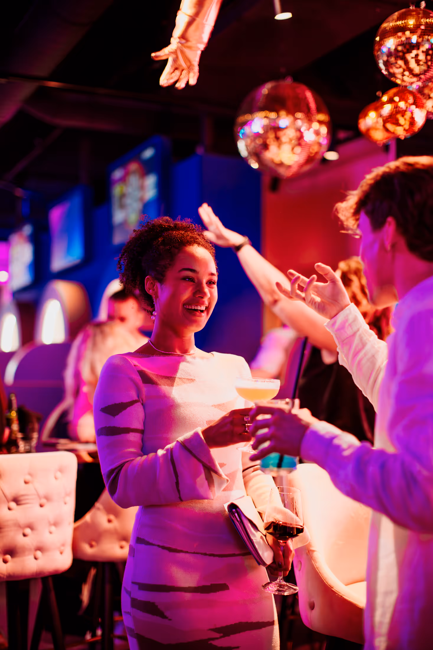 two people laughing with a cocktail in hand.