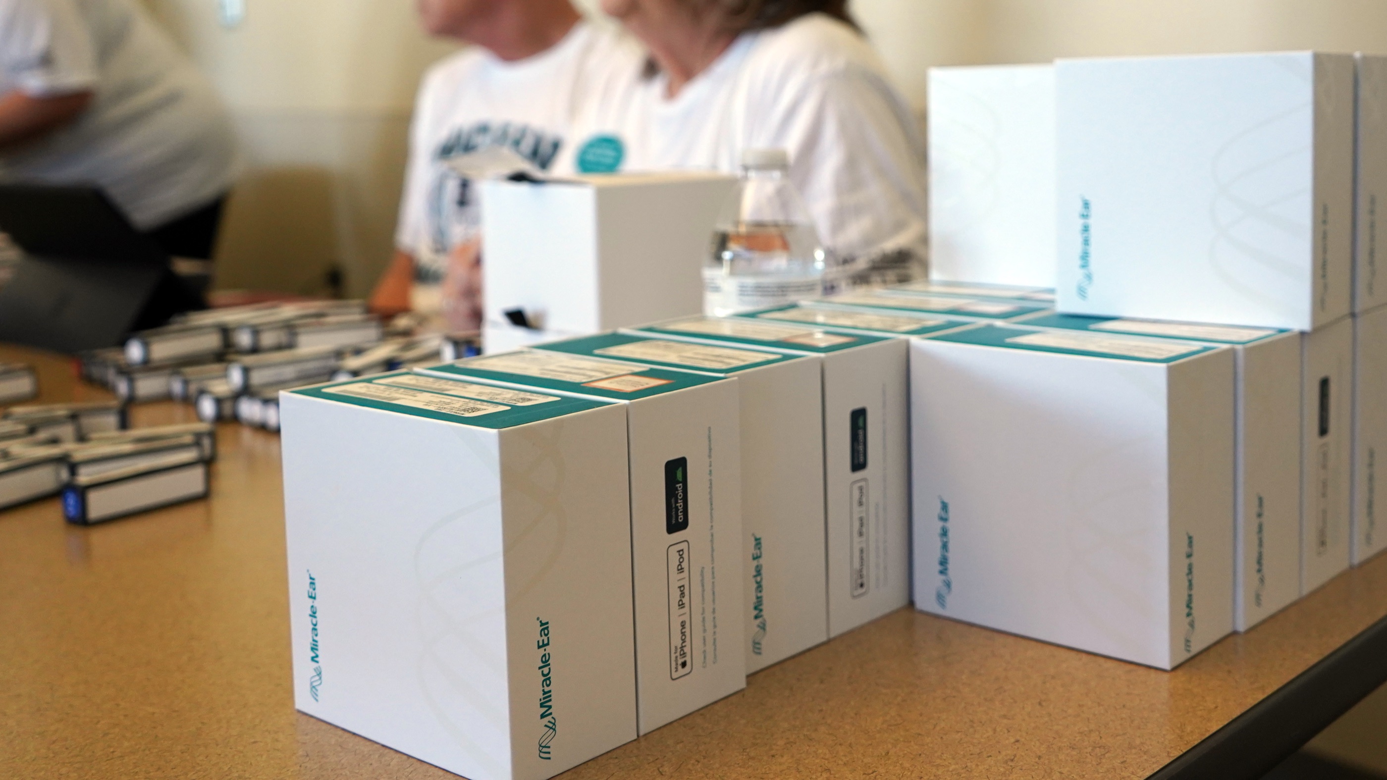 Boxes of new Miracle-Ear hearing aids stacked on a table at a fitting event