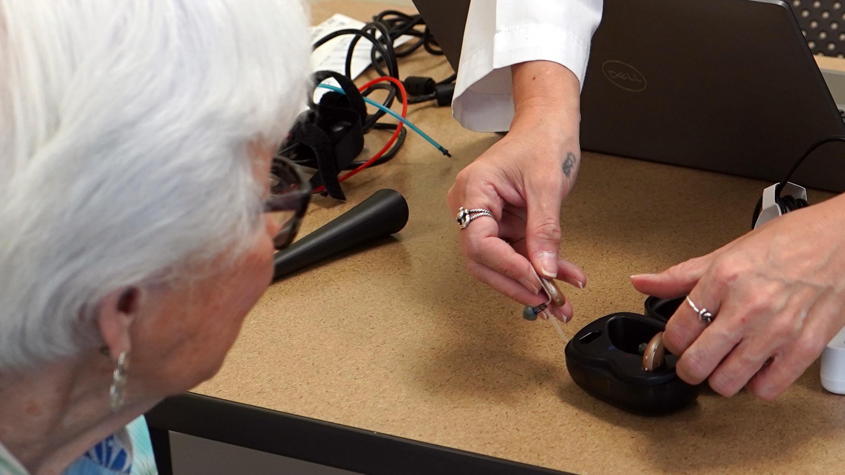 A hearing specialist shows a woman her new hearing aids in their charging case