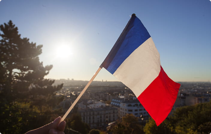 French flag held above a panoramic view of Paris rooftops