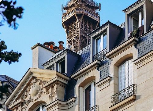 Rooftop and chimney of a traditional French property against a blue sky