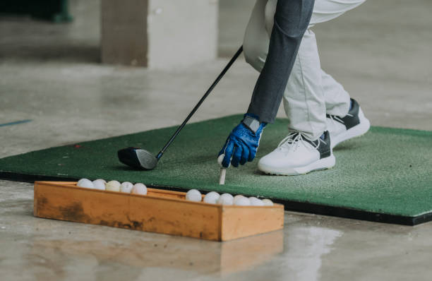 A golfer arranging a golf ball at a driving range