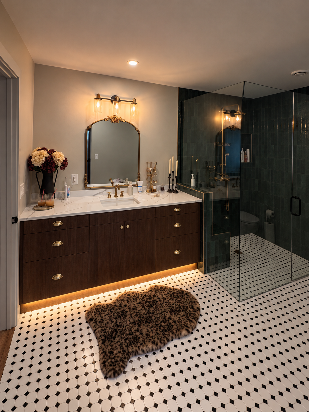 Quiet luxury basement bathroom with warm wood vanity, brass fixtures, black-and-white mosaic flooring and an oversized green tiled walk-in shower.