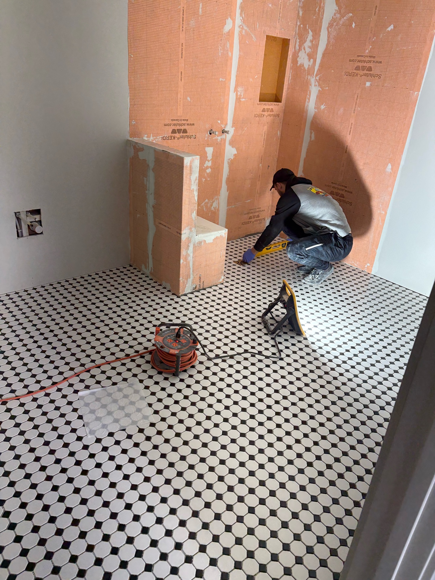 Basement bathroom under construction showing waterproofed walk-in shower, built-in bench, pony wall and recessed niche.