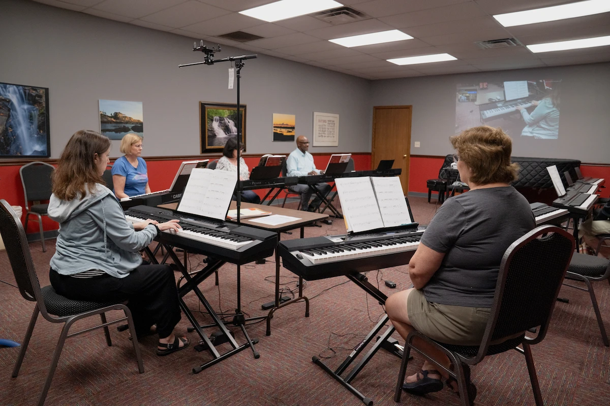 Adult group piano students practicing together in classroom setting at Cincinnati Music Academy in Kenwood.