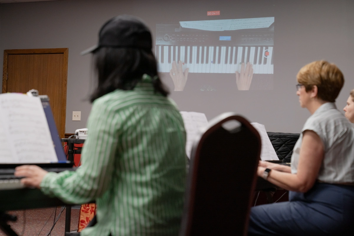 Adult piano student watching live keyboard demonstration during group piano class at Cincinnati Music Academy.