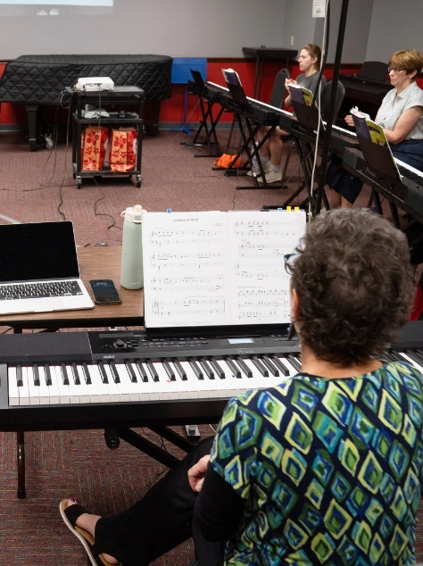 Adult students practicing together during a group piano class at Cincinnati Music Academy.