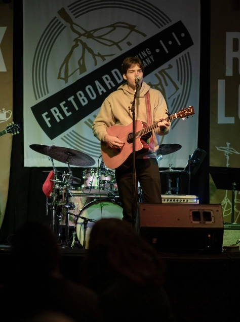 CMA student singing and playing guitar live at Fretboard Brewing during a Cincinnati Music Academy concert event.