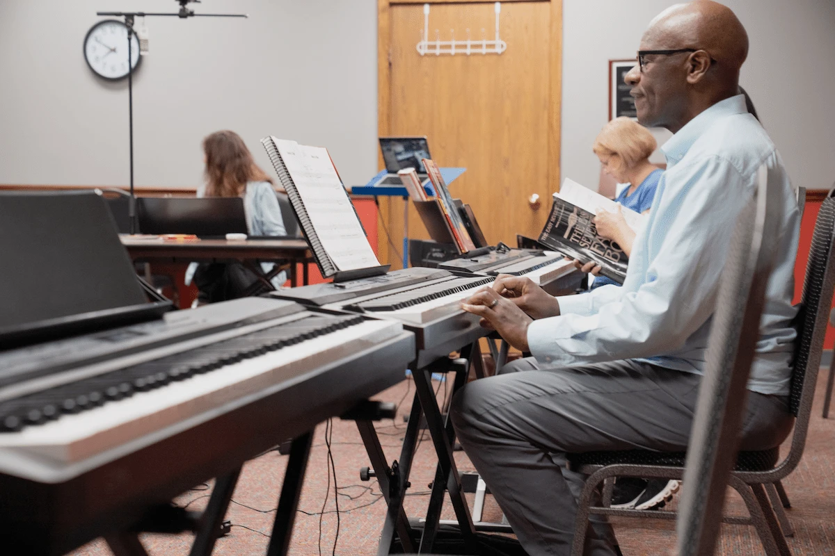 Group piano lessons at Cincinnati Music Academy with instructor teaching multiple students on keyboards in classroom