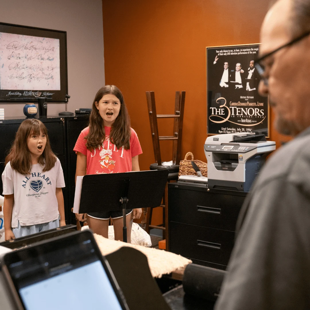 Two young students taking voice lessons with instructor at Cincinnati Music Academy, learning proper singing technique