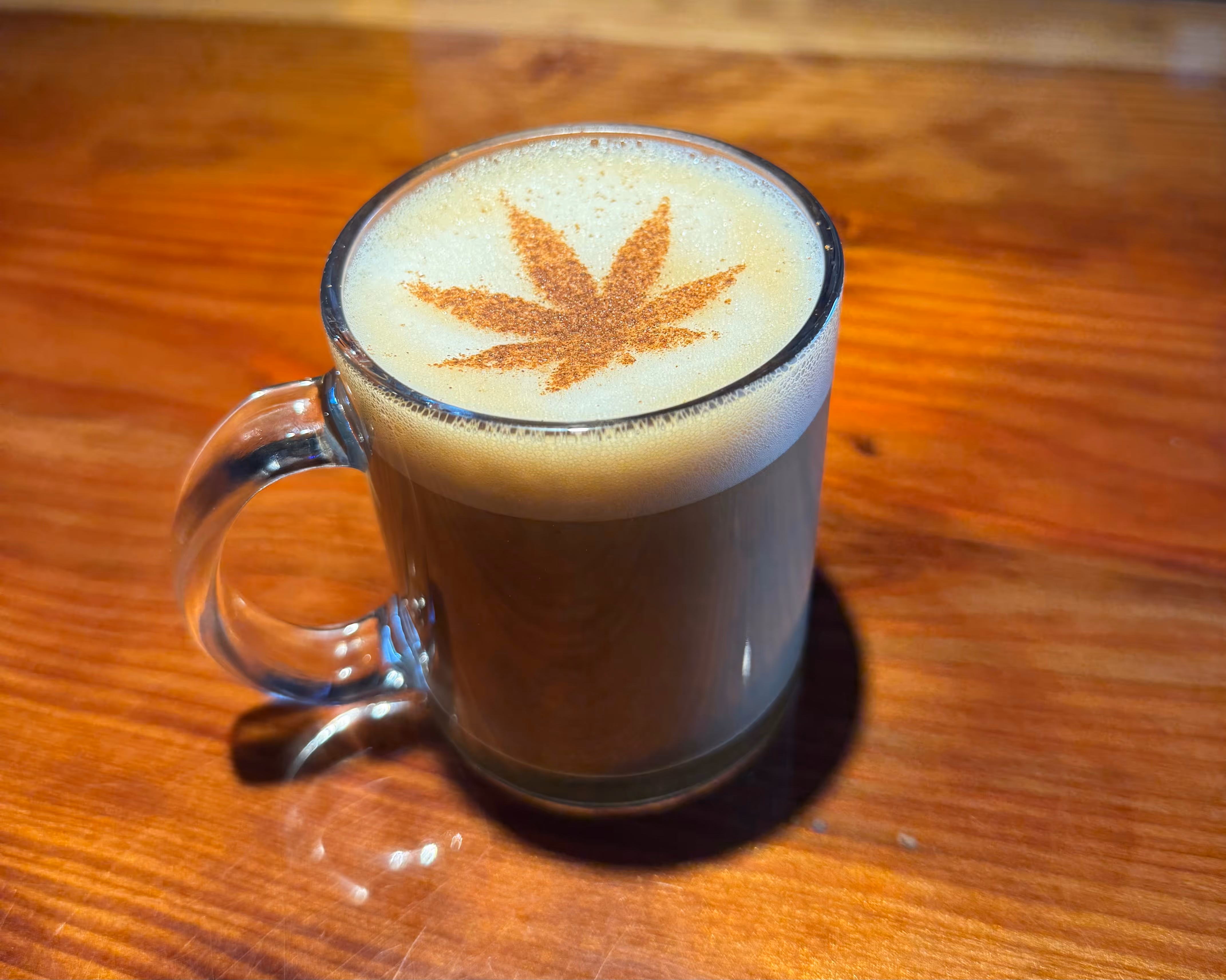 Coffee with a cannabis leaf design made out of milk foam on top.