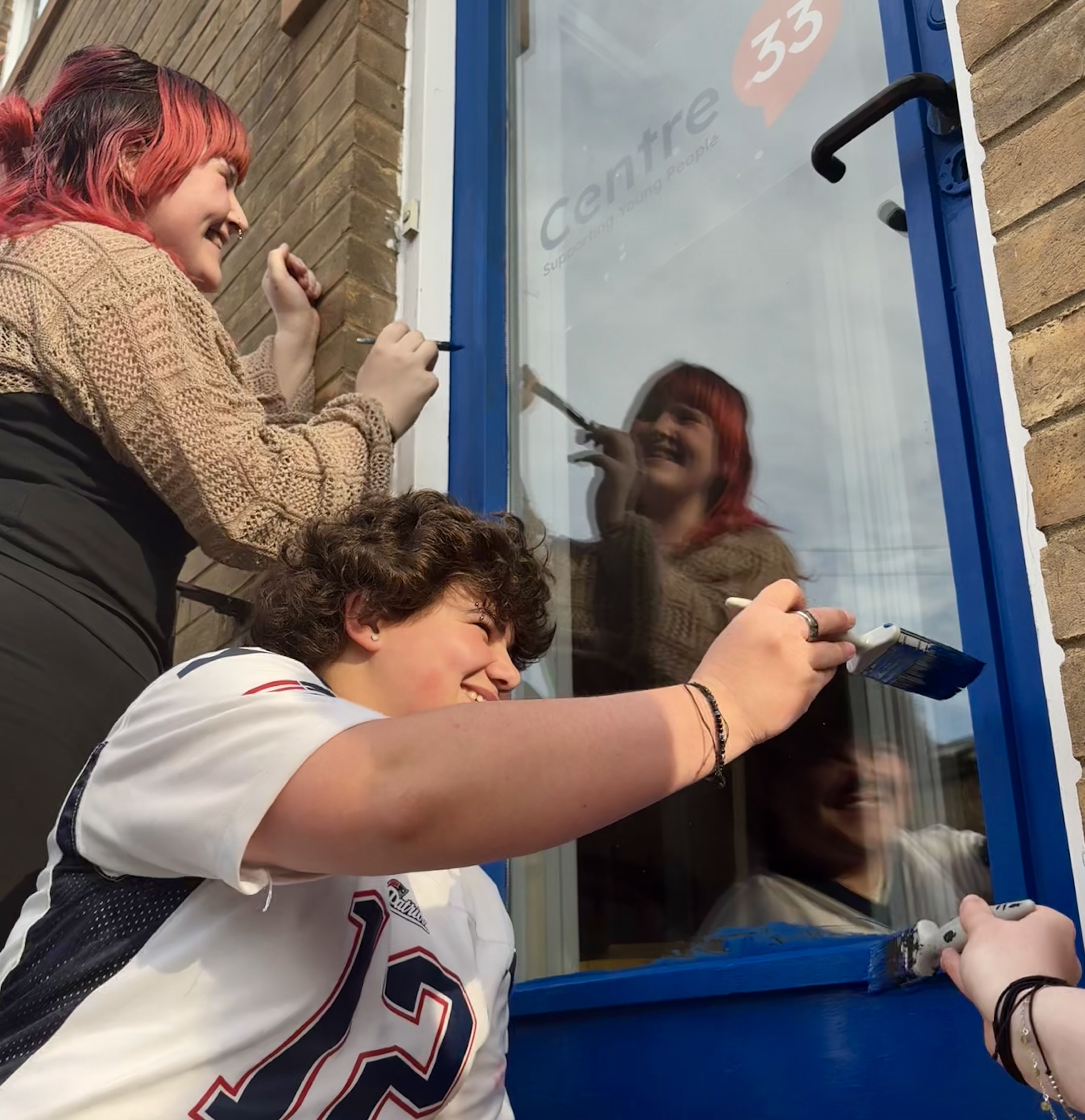 Young people paint the door of Centre 33's new Cambridge support hub.
